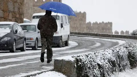 Un hombre corre con un paraguas para protegerse de la nieve en Ávila Un hombre corre con un paraguas para protegerse de la nieve en Ávila