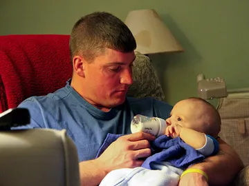 Un padre da el biberón a su hijo Un padre da el biberón a su hijo