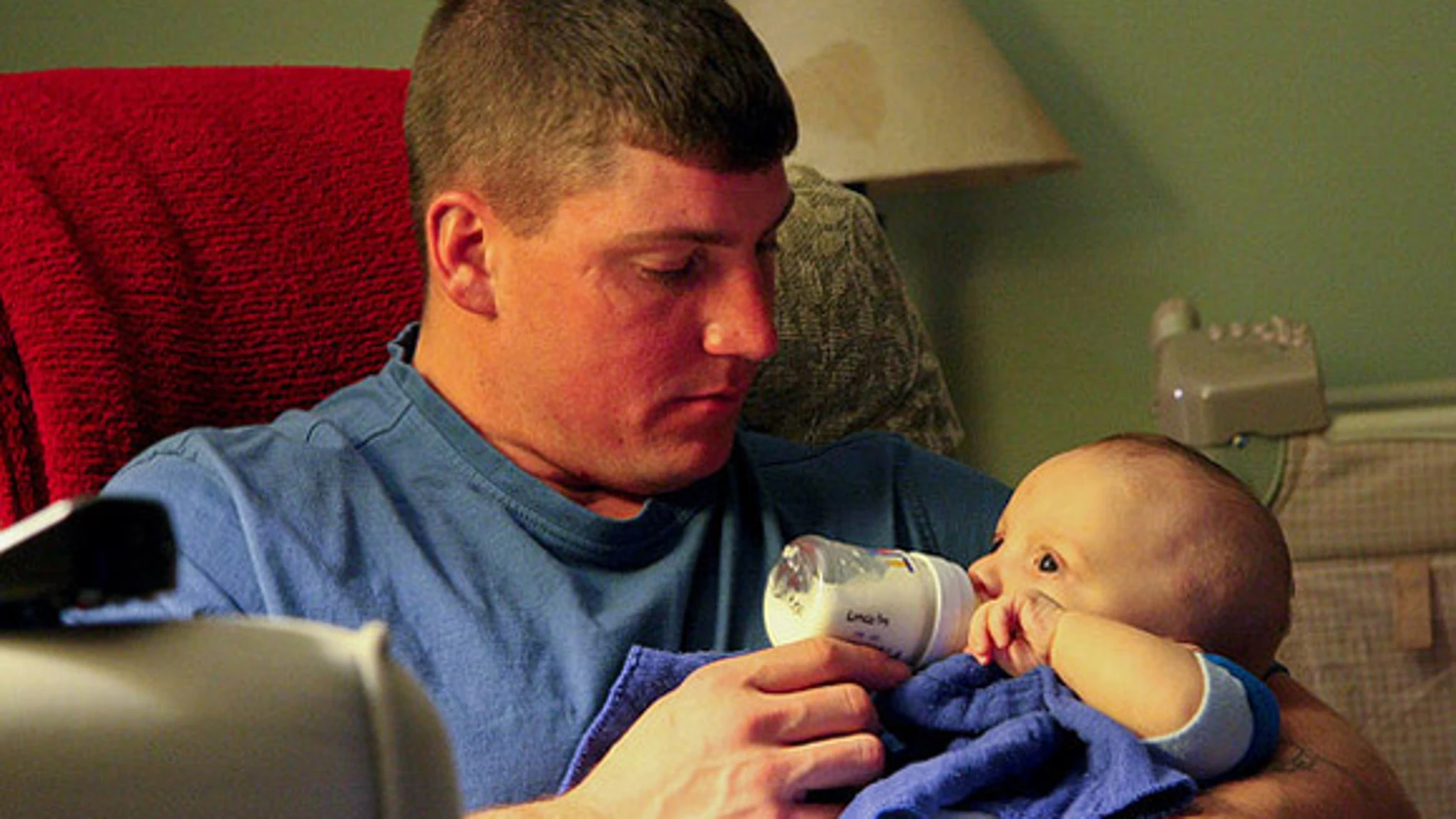 Un padre da el biberón a su hijo Un padre da el biberón a su hijo