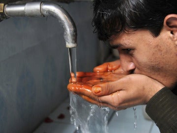 Un joven bebiendo agua de una fuente Un joven bebiendo agua de una fuente