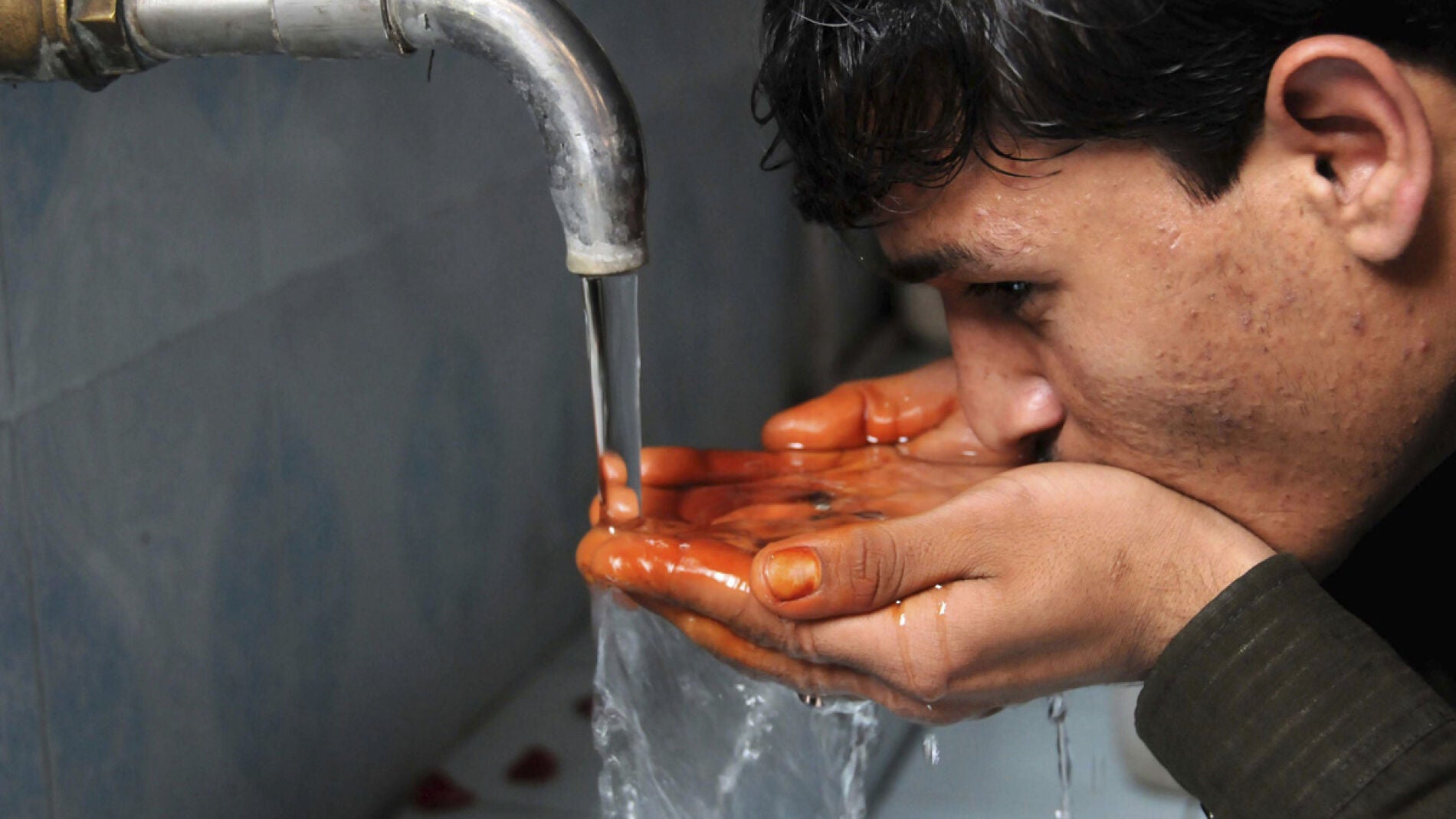 Un joven bebiendo agua de una fuente