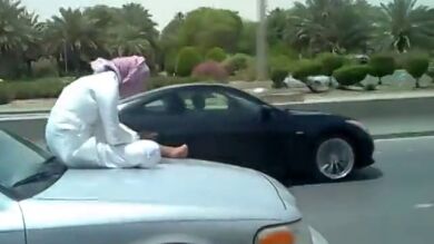 Un hombre utiliza el teléfono móvil subido al capó de un coche en marcha
