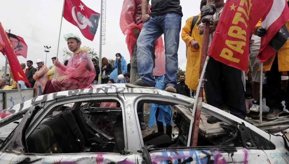 Manifestantes en un coche destrozado
