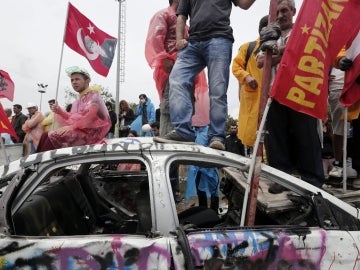 Manifestantes en un coche destrozado