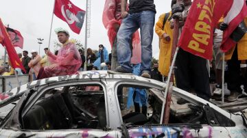 Manifestantes en un coche destrozado