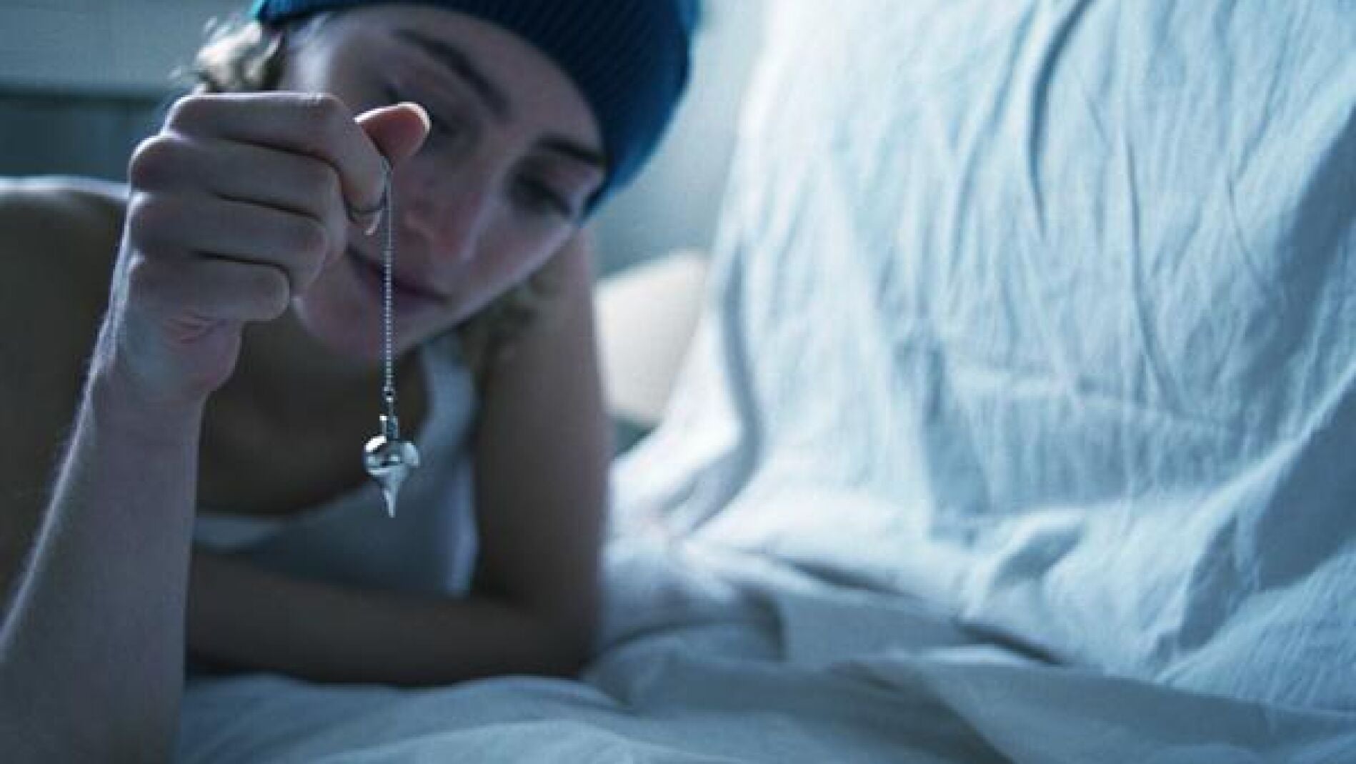 Una mujer sostiene un p&eacute;ndulo esot&eacute;rico.