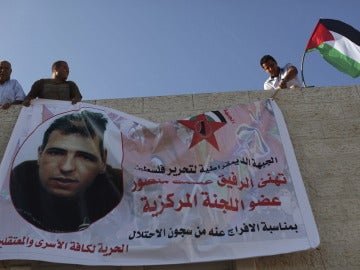 Familiares despligan una bandera con la fotografía de un preso palestino que será liberado.