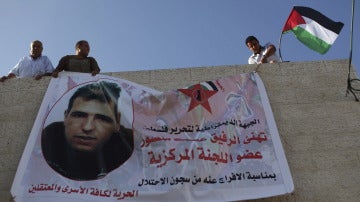 Familiares despligan una bandera con la fotografía de un preso palestino que será liberado.