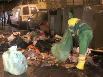 Un trabajador limpia junto a un contenedor 