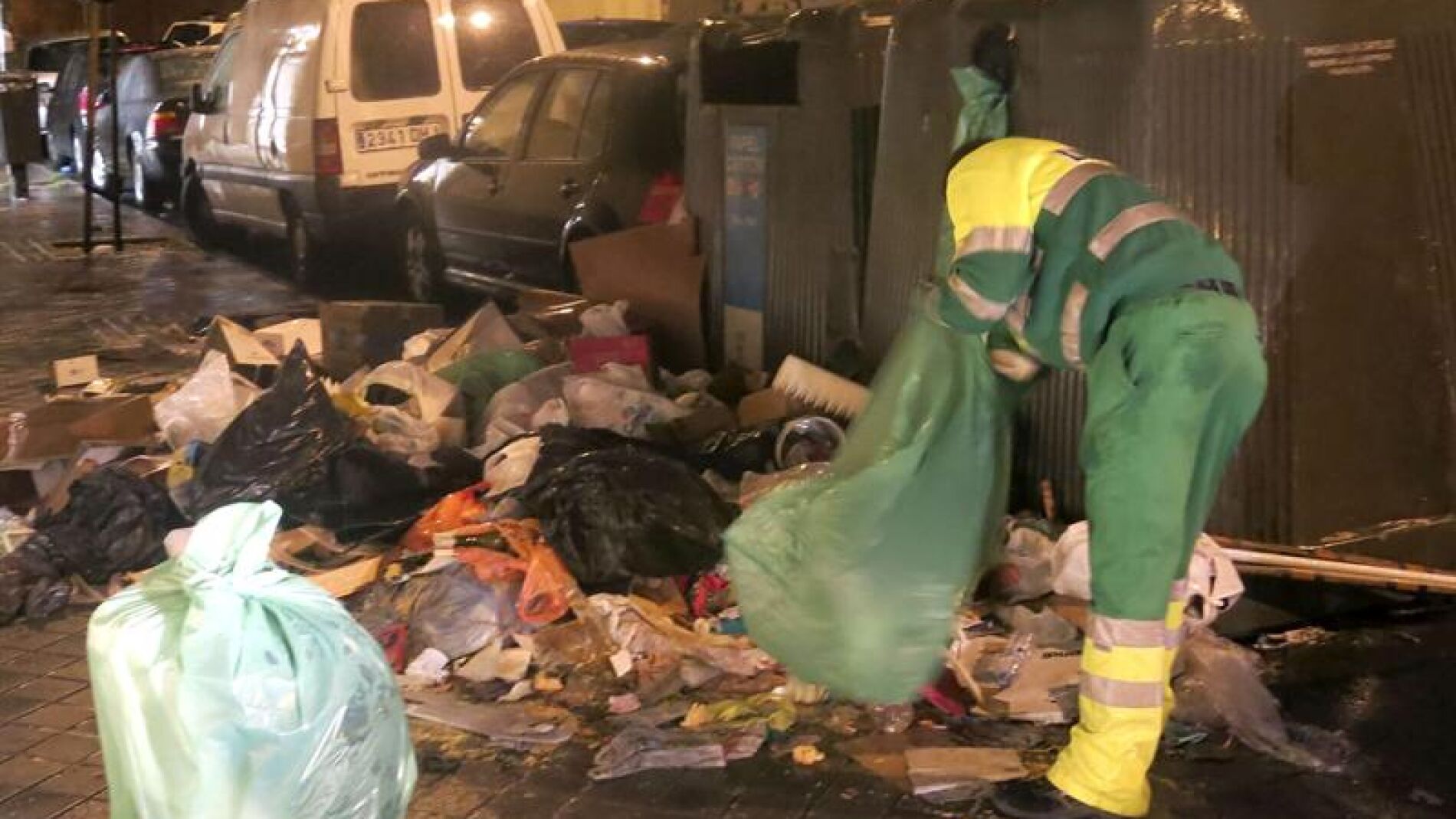 Un trabajador limpia junto a un contenedor 