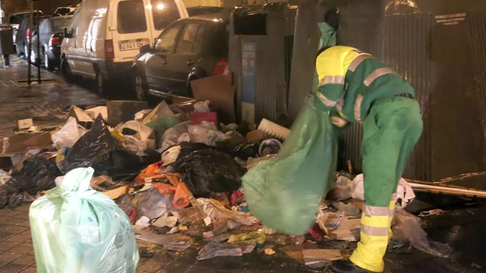 Un trabajador limpia junto a un contenedor Un trabajador limpia junto a un contenedor