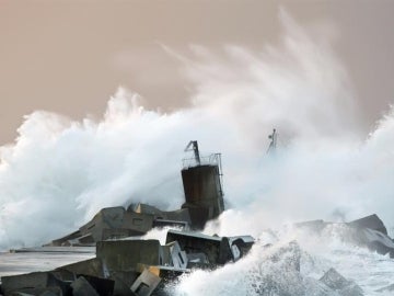 Una ola rompe contra la costa en la playa de San Juan de Nieva en Avilés.