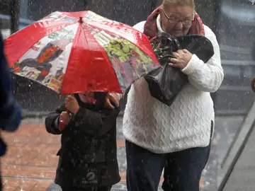 Una señora y un niño bajo la lluvia Una señora y un niño bajo la lluvia
