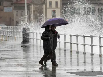 Dos personas pasean por Gijón bajo la lluvia Dos personas pasean por Gijón bajo la lluvia