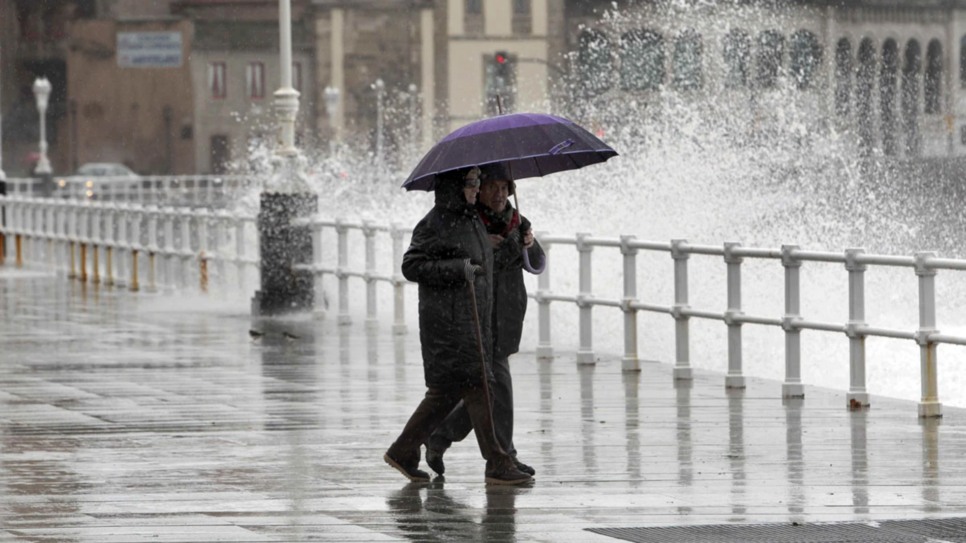 Dos personas pasean por Gijón bajo la lluvia Dos personas pasean por Gijón bajo la lluvia