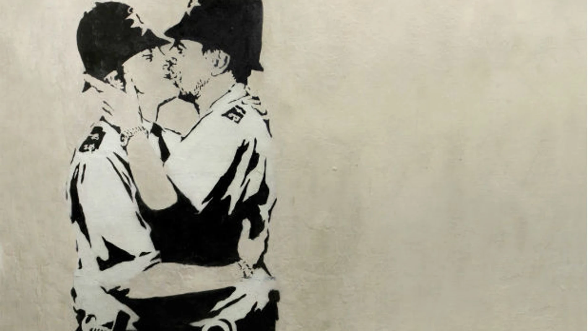 Obra de Banksy en blanco y negro, en la que aparecen dos policía británicos besándose. Obra de Banksy en blanco y negro, en la que aparecen dos policía británicos besándose.
