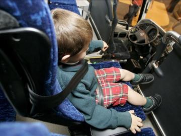 Menor con cinturón de seguridad en un autobús escolar Menor con cinturón de seguridad en un autobús escolar
