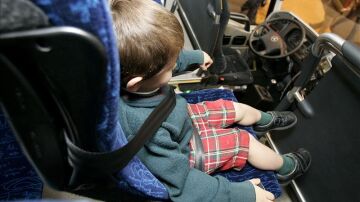 Menor con cinturón de seguridad en un autobús escolar