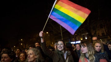 una muchedumbre iza la bandera gay