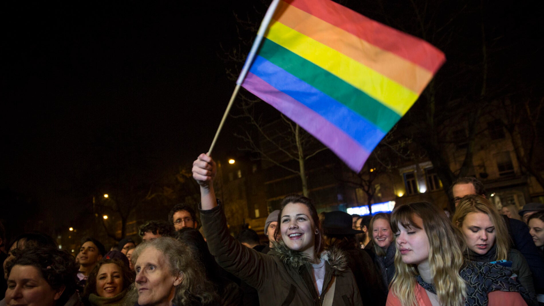 una muchedumbre iza la bandera gay