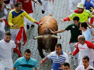 Dos mozos tocan a un toro durante un encierro de San Fermín