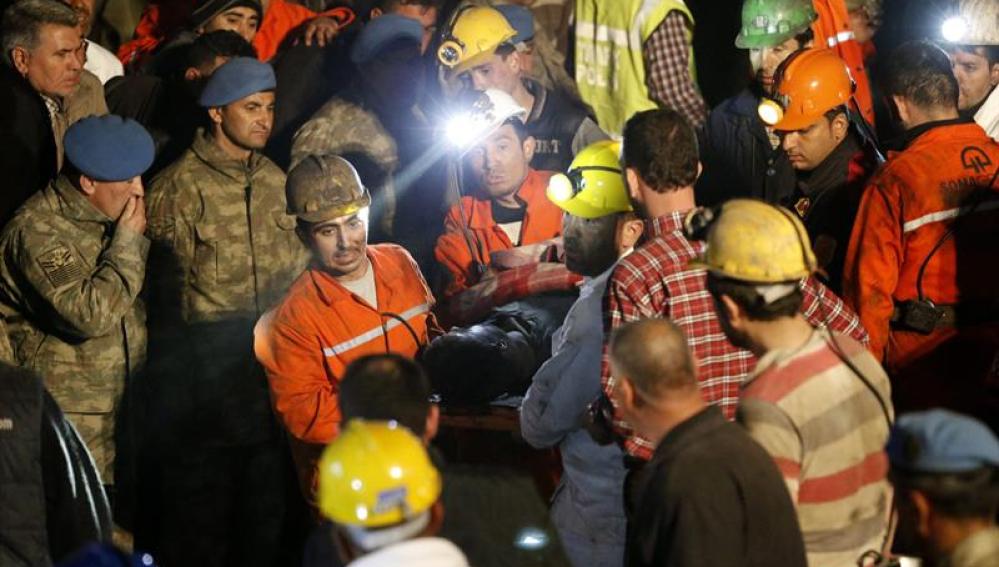 Miembros del equipo de rescate trasladan a un minero muerto