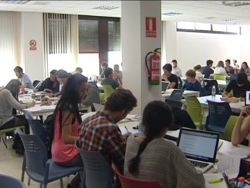 Estudiantes repasan apuntes en una biblioteca Estudiantes repasan apuntes en una biblioteca