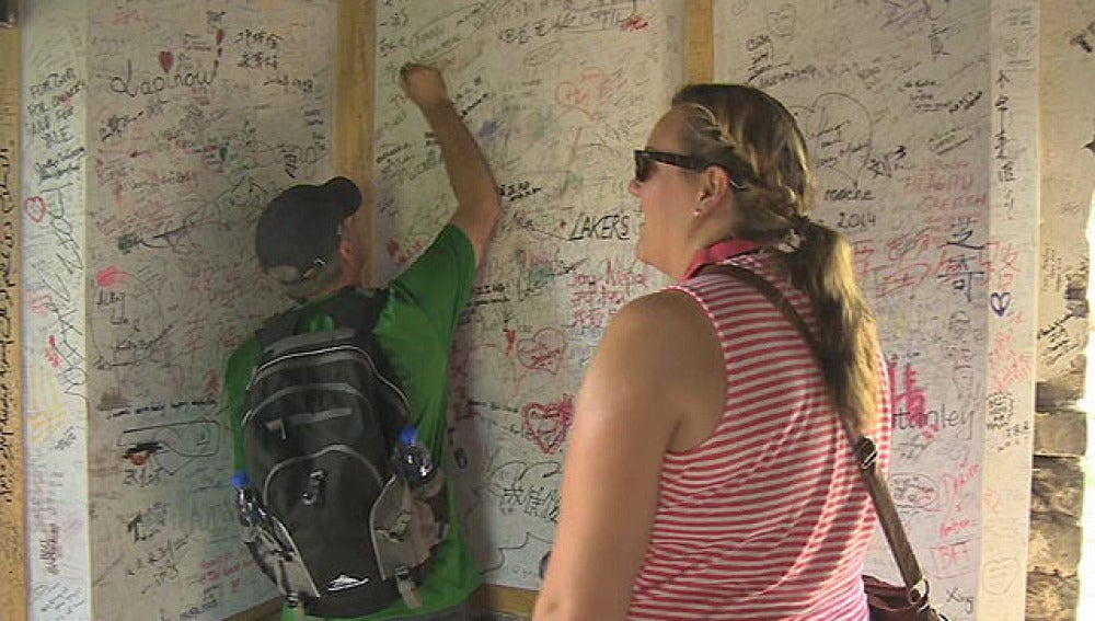 Dos turistas dejan su firma en la tela rígida instalada en la Gran Muralla china
