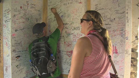 Dos turistas dejan su firma en la tela r&iacute;gida instalada en la Gran Muralla china