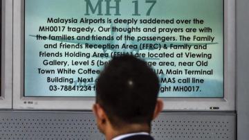 Un pasajero observa una pantalla en la que se lee "Rezo por MH17"