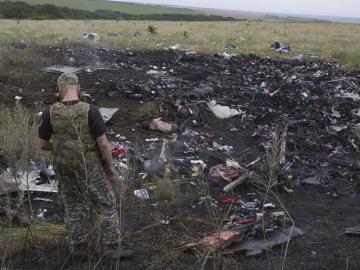 Un rebelde prorruso observa varios cadáveres entre los restos del avión Boeing 777 del vuelo MH17