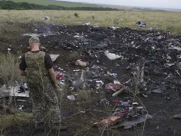 Un rebelde prorruso observa varios cadáveres entre los restos del avión Boeing 777 del vuelo MH17 Un rebelde prorruso observa varios cadáveres entre los restos del avión Boeing 777 del vuelo MH17