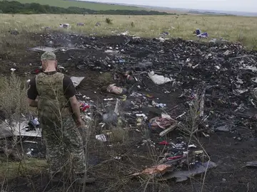 Un rebelde prorruso observa varios cadáveres entre los restos del avión Boeing 777 del vuelo MH17 Un rebelde prorruso observa varios cadáveres entre los restos del avión Boeing 777 del vuelo MH17