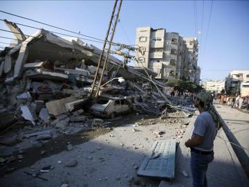 Unos palestinos observan un edificio destruído por proyectiles en Gaza