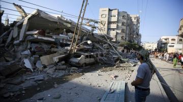 Unos palestinos observan un edificio destruído por proyectiles en Gaza