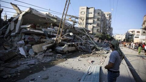 Unos palestinos observan un edificio destru&iacute;do por proyectiles en Gaza