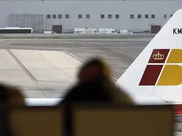 Dos pasajeros contemplan un avión de Iberia Dos pasajeros contemplan un avión de Iberia