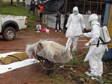 Varias enfermeras desinfectan una víctima del ébola en la calle 