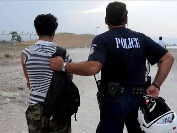 un policía griego con un inmigrante ilegal en la localidad de Kandare un policía griego con un inmigrante ilegal en la localidad de Kandare