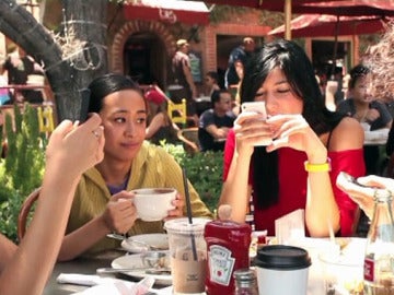 Tres personas consultan su teléfono móvil durante una comida