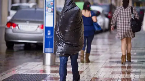 Se resguarda de la lluvia bajo una bolsa Se resguarda de la lluvia bajo una bolsa