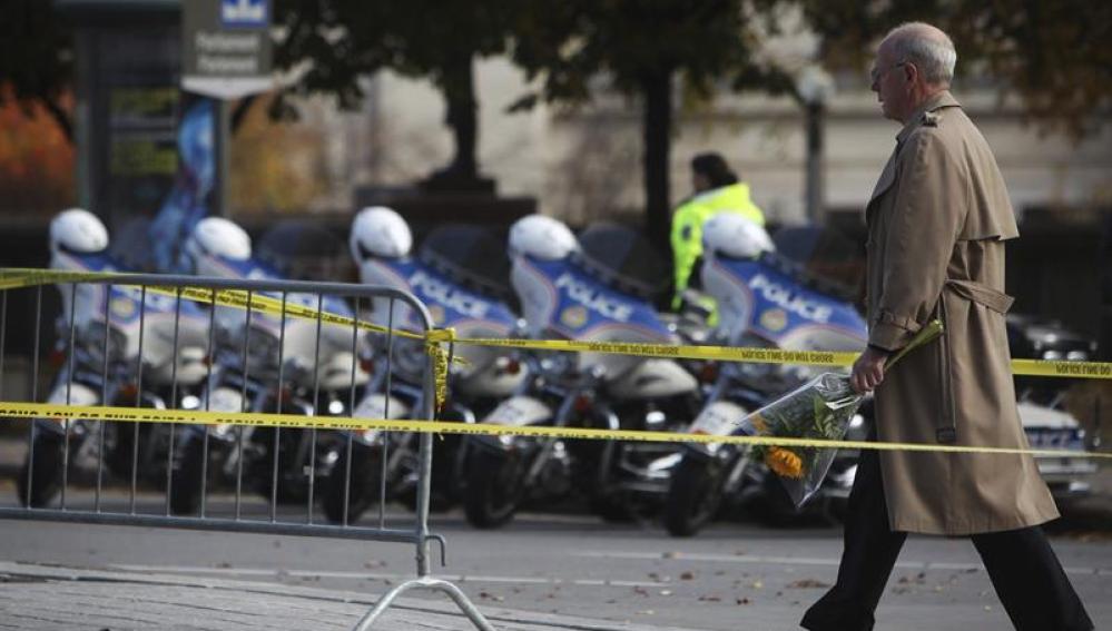 Un hombre se dispone a colocar flores en memoria del soldado asesinado por Michael Zehaf-Bibeau