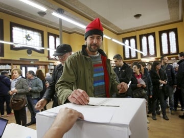 Un ciudadano, con barretina, deposita su papeleta