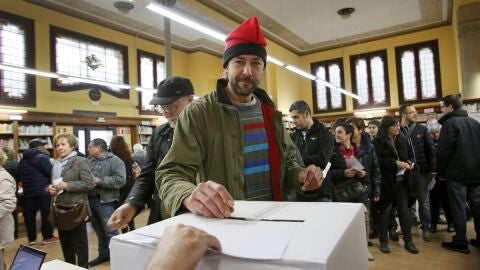Un ciudadano, con barretina, deposita su papeleta