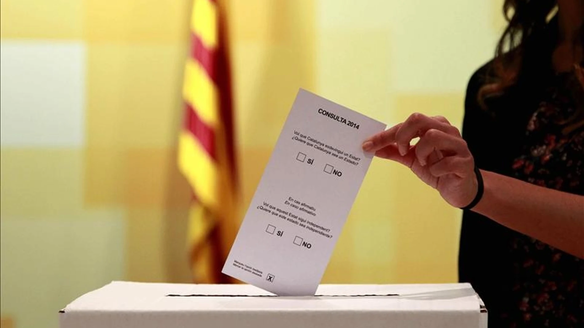 Una persona introduce una papeleta en una urna el 9N Una persona introduce una papeleta en una urna el 9N