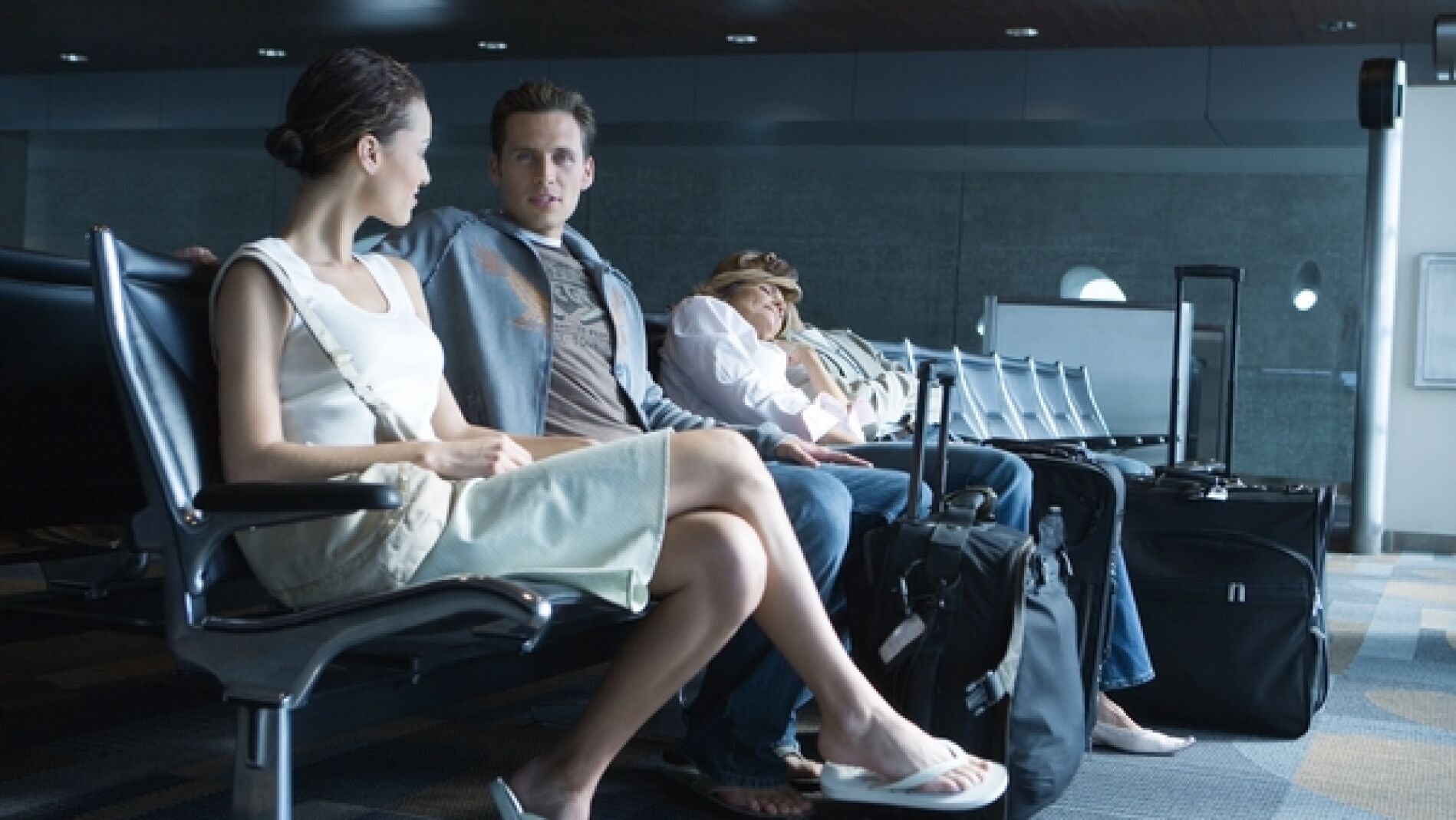 Dos j&oacute;venes esperan en un aeropuerto.