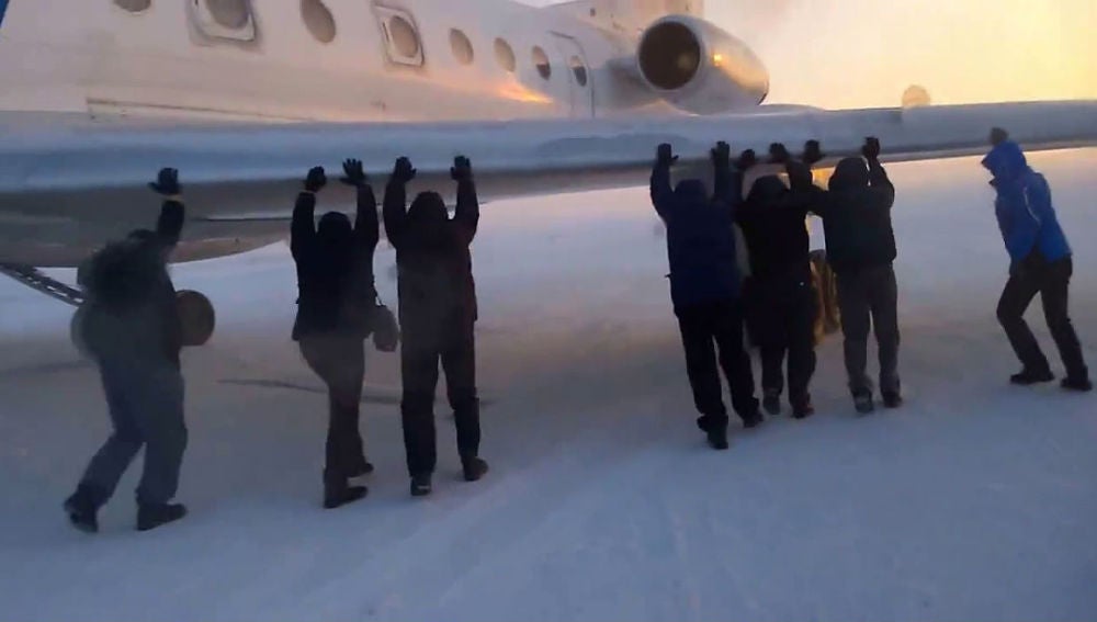 Pasajeros empujan su avión por una pista helada en Siberia