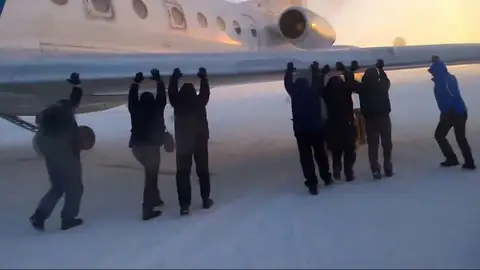 Pasajeros empujan su avión por una pista helada en Siberia Pasajeros empujan su avión por una pista helada en Siberia