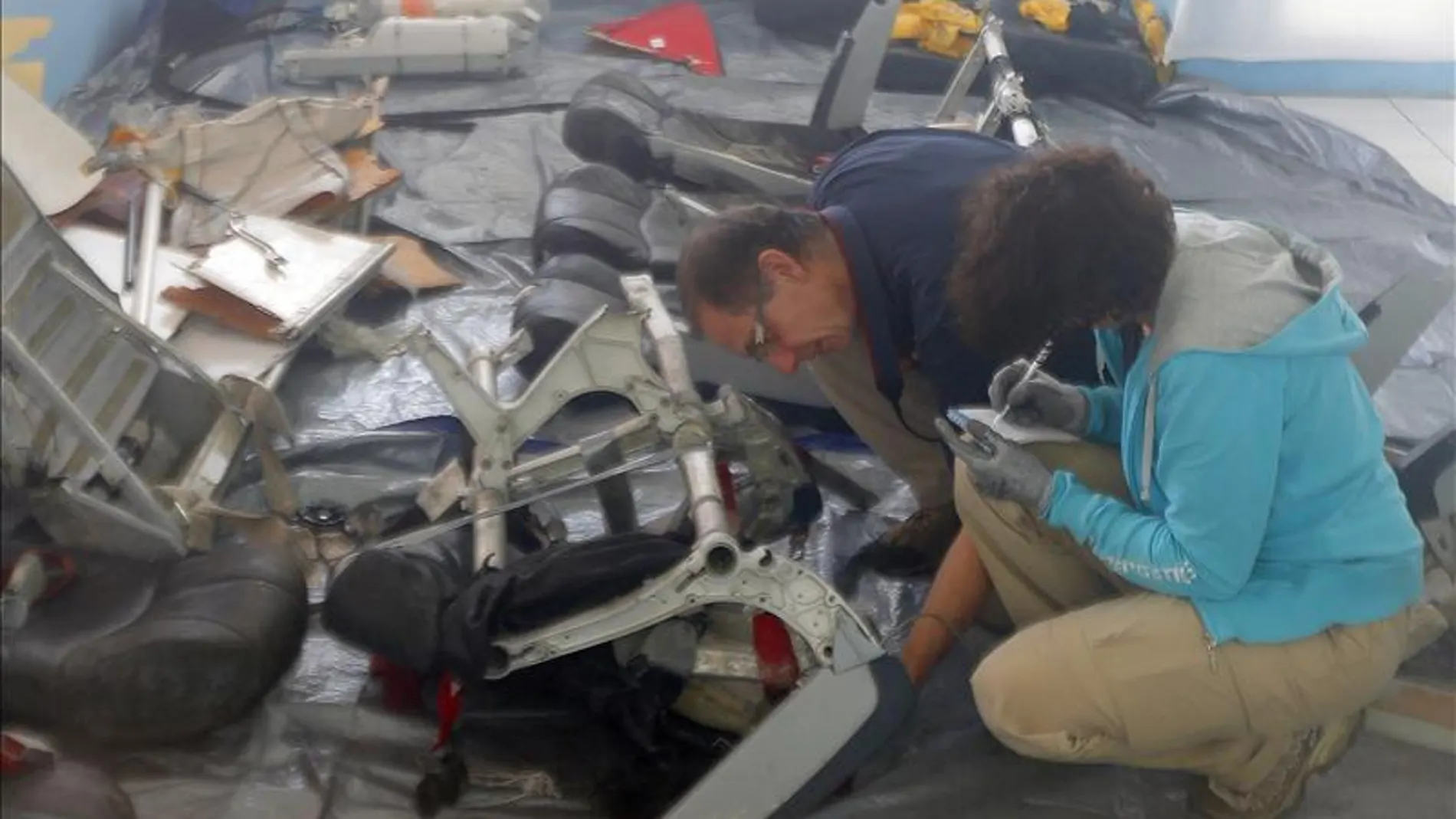 Especialistas revisan una silla del avión siniestrado. Especialistas revisan una silla del avión siniestrado.