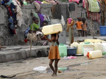 Una niña huérfana carga con un bidón para el agua en Bombai (India).